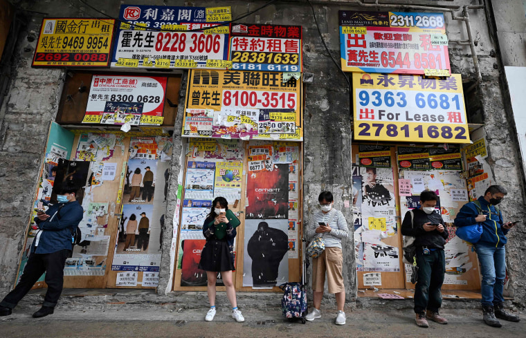 Des gens utilisent leur téléphone portable devant un magasin fermé à Hong Kong le 1er novembre 2022. 