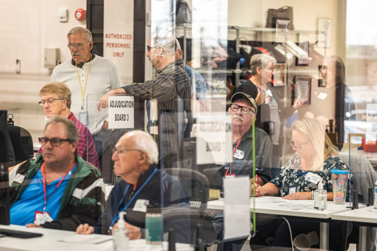 Poll workers handle ballots in the presence of observers from both Democrat and Republican parties at the Maricopa County Tabulation and Elections Center in Phoenix on Oct. 25, 2022.