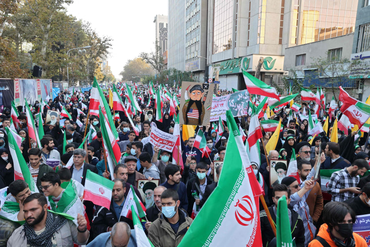 Iranians wave their country's national flags as they take part in a rally outside the former US embassy in Tehran, on Nov. 4, 2022.