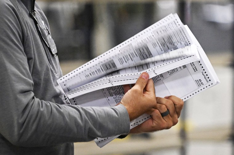 Poll workers process ballots at an elections warehouse
