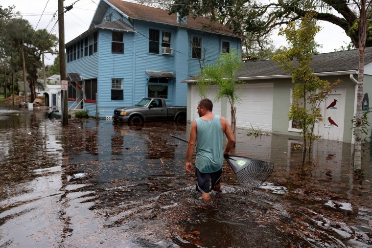 A man walks through flood water that surround his home in Daytona Beach, Fla.