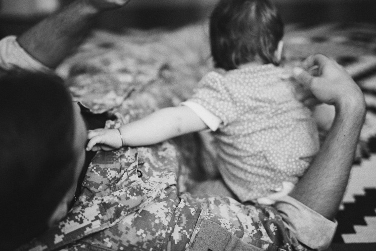 A soldier at home with child seen from the back.