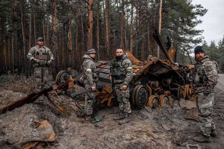 Ukrainian soldiers and volunteer fighters inspect a destroyed Russian tank in eastern Ukraine on Nov. 10, 2022.