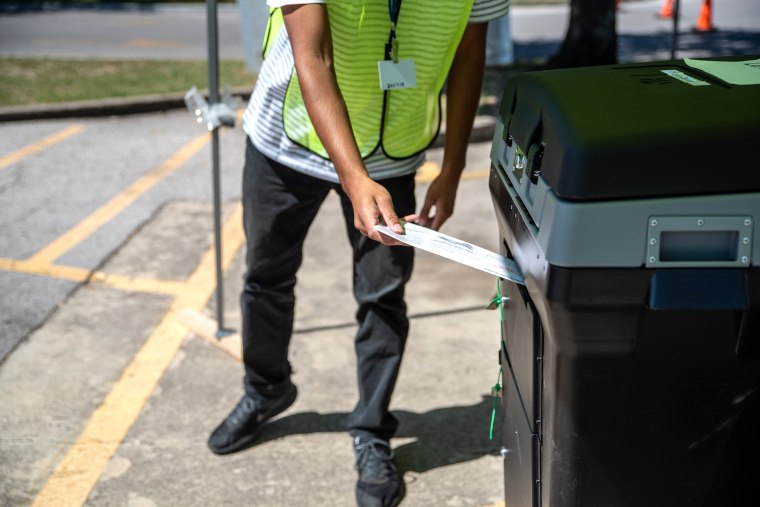 A worker puts a ballot into a secure box at a drive-thru mail ballot hand delivery center in Austin, Texas, U.S., on Friday, Oct. 2, 2020. Governor Abbott announced that every county in Texas would only be allowed one drop off box for mail in ballots, citing concerns of voter fraud.