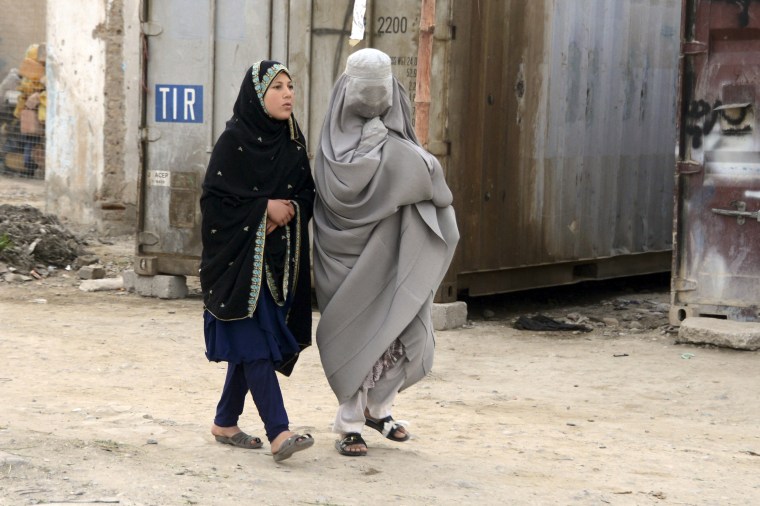 A burqa-clad woman and a girl walk along a street in Kandahar on March 5, 2022.