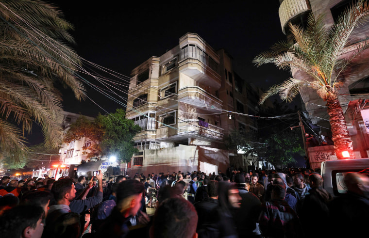 Palestinians gather in front of a building as firefighters extinguish a fire which broke out in one of the apartments in the Jabalia refugee camp in the northern Gaza strip, on Nov. 17, 2022.