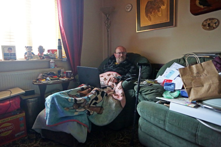 Man sitting amidst cardboard boxes on floor in living room of new