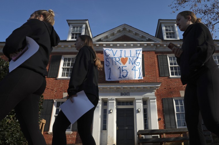 Students walk past a fraternity house with a banner memorializing three University of Virginia football players killed during an overnight shooting at the university on Nov. 14, 2022 in Charlottesville.