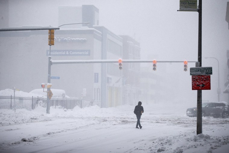 A person crosses Ellicott Street as snow falls, in Buffalo, N.Y., on Nov. 18, 2022.  