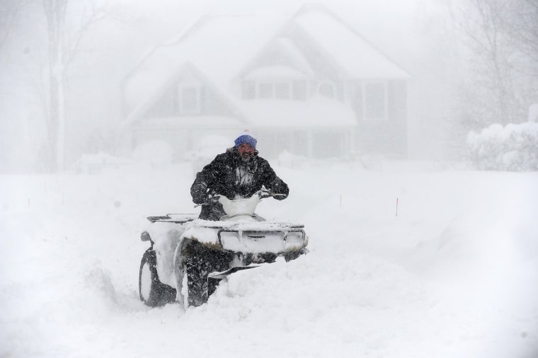 A man uses an ATV to dig out in front of a home after an intense lake-effect snowstorm impacted the area in Hamburg, N.Y., on Nov. 18, 2022. 