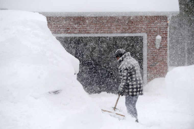 A person digs out their car outside a home after an intense lake-effect snowstorm impacted the area in Hamburg, N.Y., on Nov. 18, 2022