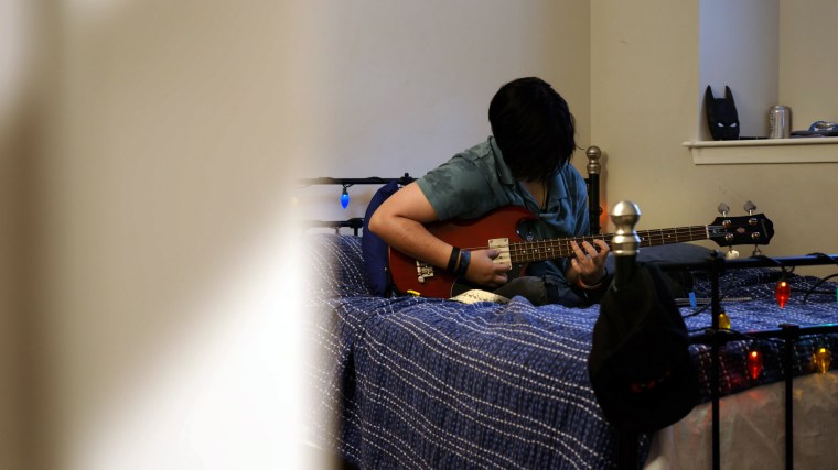 Noah, 16, plays his guitar in the bedroom of his Texas home.