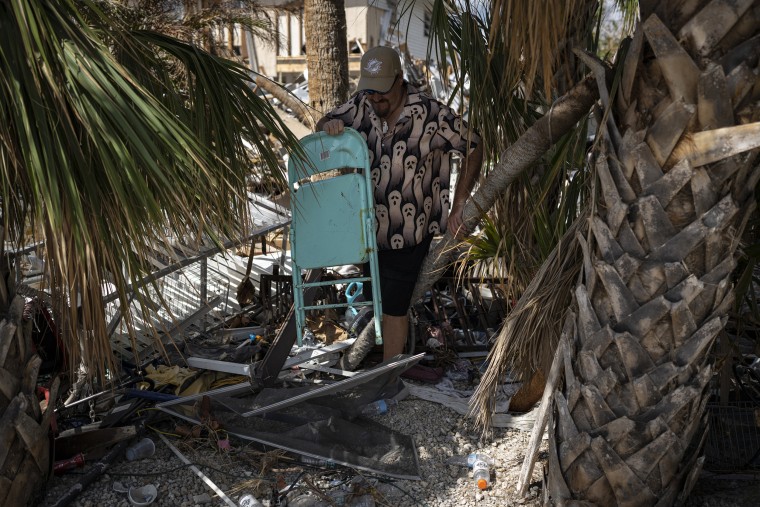 Michael Yost finds a chair at the destroyed home of his friend Mitch Pacyna.
