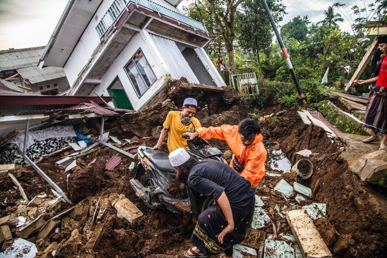 Villagers salvage items from damaged houses following a 5.6-magnitude earthquake that killed at least 162 people, with hundreds injured and others missing in Cianjur on November 22, 2022. 