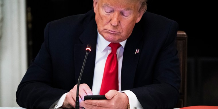 Image: President Donald J. Trump uses his cellphone as he during a roundtable discussion at the White House.