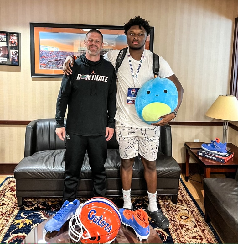 T.A. Cunningham holding his stuffed animal Baby Chop, who accompanies him on recruiting trips, with the head coach at Florida University.