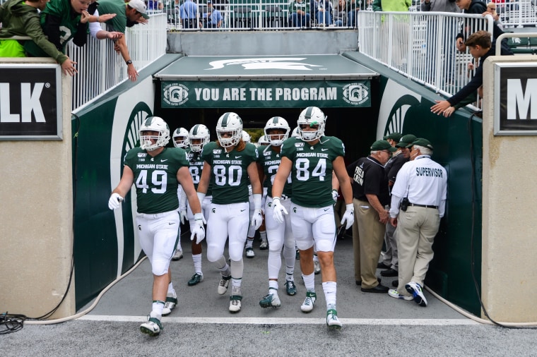 Members of the Michigan State football team exit the tunnel