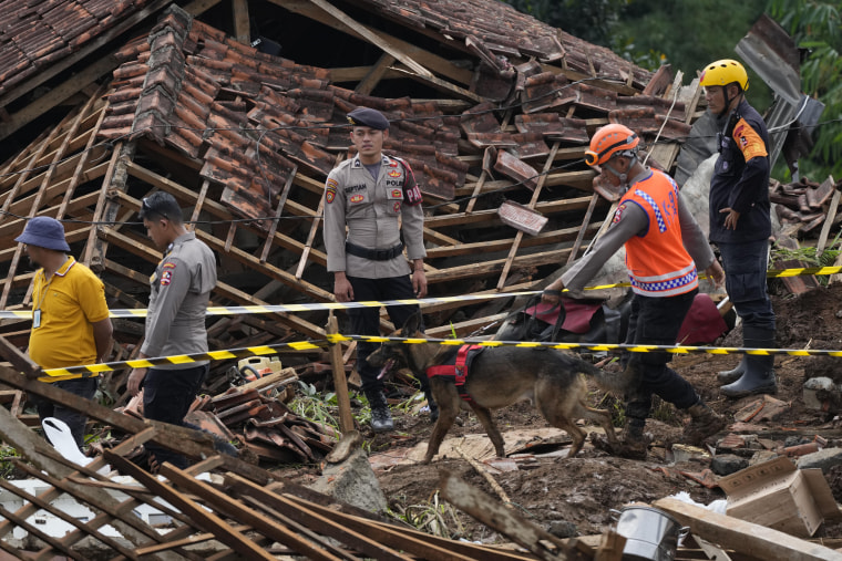 A police officer leads a sniffer dog on Thursday during the search for victims in a village hit by an earthquake-triggered landslide in Cianjur, Indonesia.
