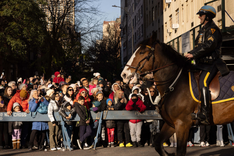 A mounted NYPD officer smiles as people take pictures during the parade.