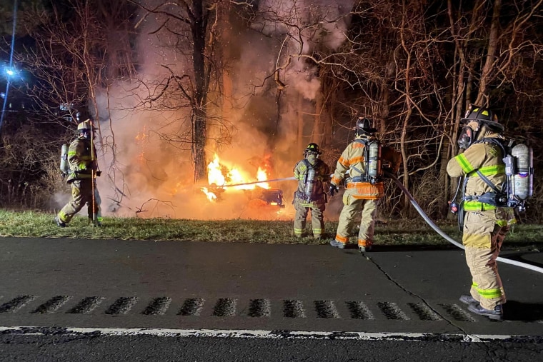 Firefighters work to extinguish a burning car in Brookfield, Conn., on Nov. 26, 2022.
