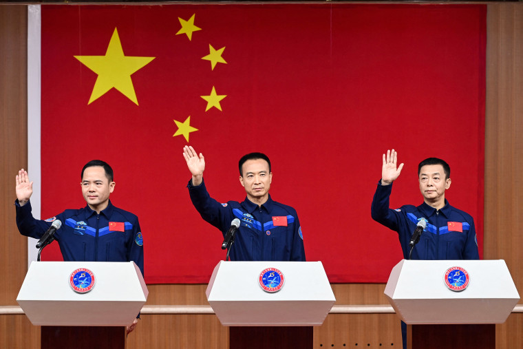 Chinese astronauts Zhang Lu, left, Fei Junlong, center, and Deng Qingming, the crew of the Shenzhou-15 spaceflight mission, wave at a press conference at the Jiuquan Satellite Launch Centre in the Gansu province on Nov. 28, 2022, a day before the scheduled launch.