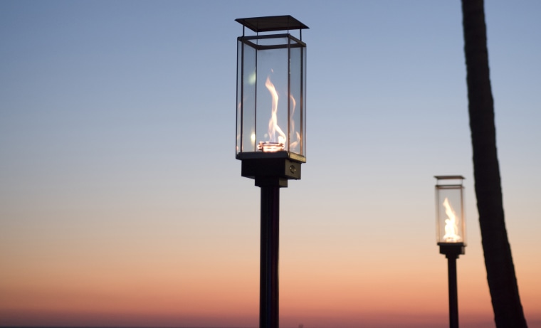 Lantern torch lights on a tropical beach at sunset.