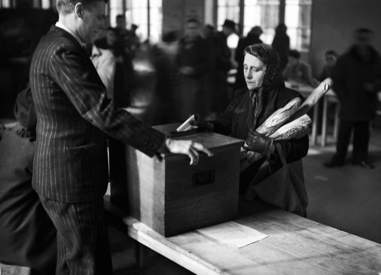  A woman casts her vote with baguettes in her arm on Nov. 10, 1946, in Paris.