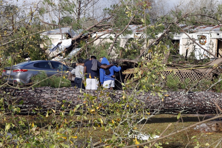Friends and family pray outside a damaged mobile home, in Flatwood, Alabama.