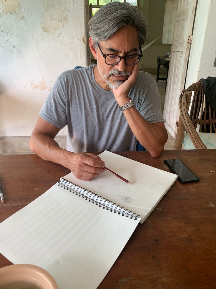 Gerardo Aldana y Villalobos, hombre latino de anteojos, bosqueja glifos mayas en un cuaderno
