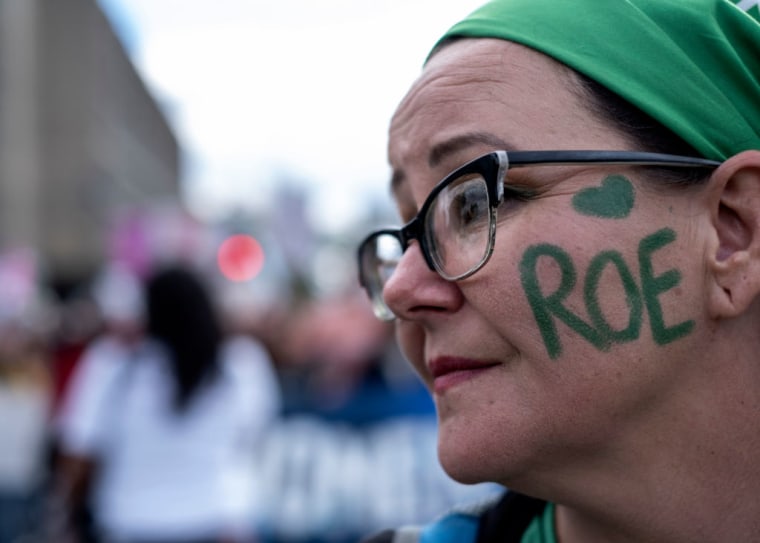 An abortion rights activist painted LOVE ROE on her cheek as