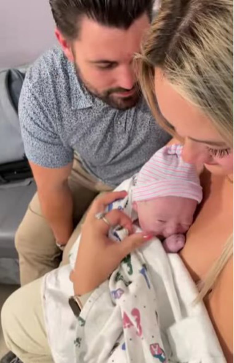 A young man and woman hold an infant child in their arms.