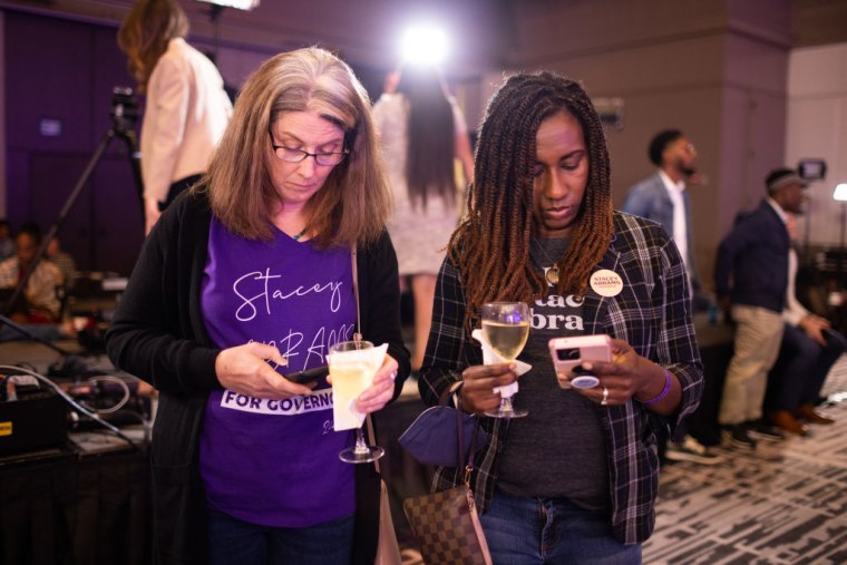 Dos mujeres consultan su teléfono celular mientras esperan los resultados sobre la elección del gobernador de Georgia, el 8 de noviembre de 2022 en Atlanta.