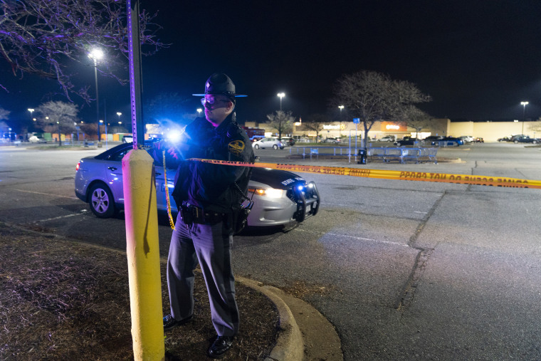 Un policía estatal de Virginia vuelve a atar la cinta de la escena del crimen mientras las fuerzas del orden trabajan en la escena de un tiroteo masivo en un Walmart, el miércoles 23 de noviembre de 2022, en Chesapeake, Virginia.