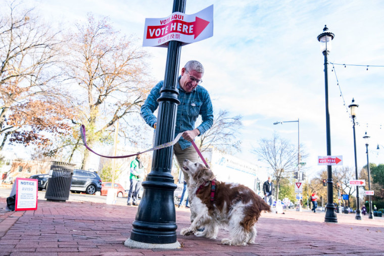 Un hombre amarra a su perro a una columna para ir a votar en Washington, D.C., el 8 de noviembre de 2022