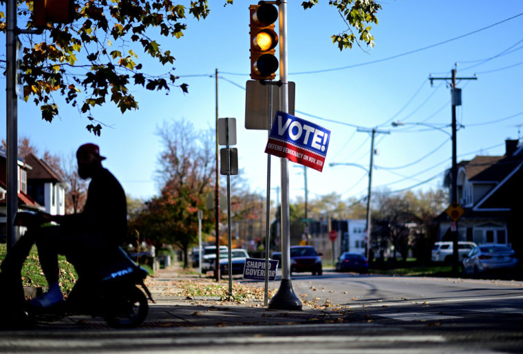 Un hombre pasa junto a una pancarta que dice: vote, defienda la democracia este 8 de noviembre colocada en un poste.  colocado en un poste de la calle en Philadelphia, Pennsylvania.