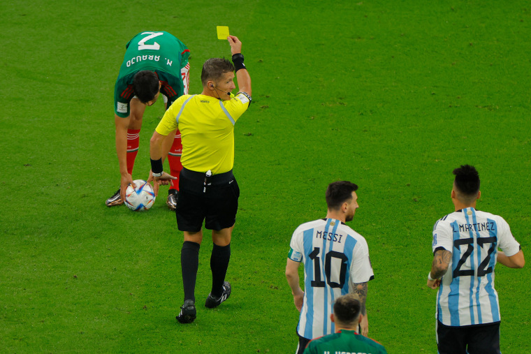 El árbitro italiano Daniele Orsato muestra una tarjeta amarilla al defensor de México Néstor Araujo.