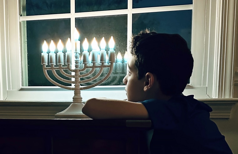 The author's son gazes at a menorah placed purposefully in front of the window.