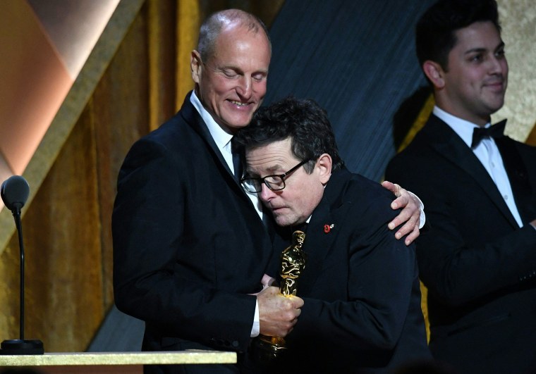 Honoree Canadian-American actor Michael J. Fox (R) is hugged by US actor Woody Harrelson as Fox arrives on stage to accept his award during the Academy of Motion Picture Arts and Sciences' 13th Annual Governors Awards at the Fairmont Century Plaza in Los 