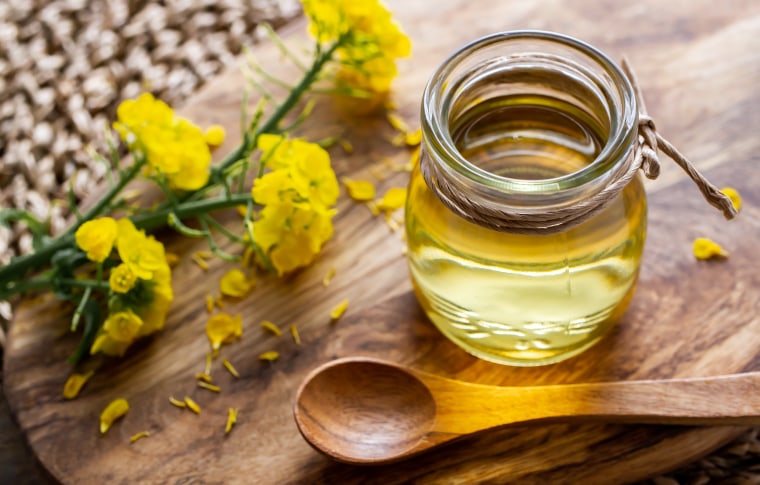 Jar of rapeseed oil (canola), and rape blossoms.