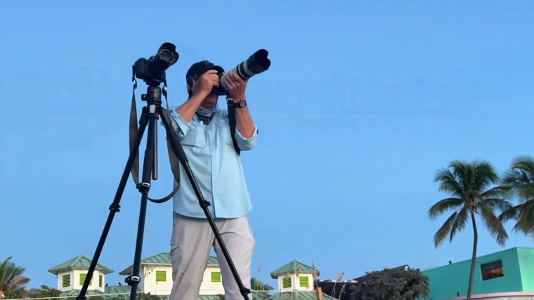 Mark Potter is seen taking a photo of the sky during the daytime.