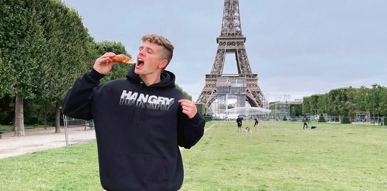 Tommy Winkler in Paris in the summer of 2021 about to bite into a croissant.