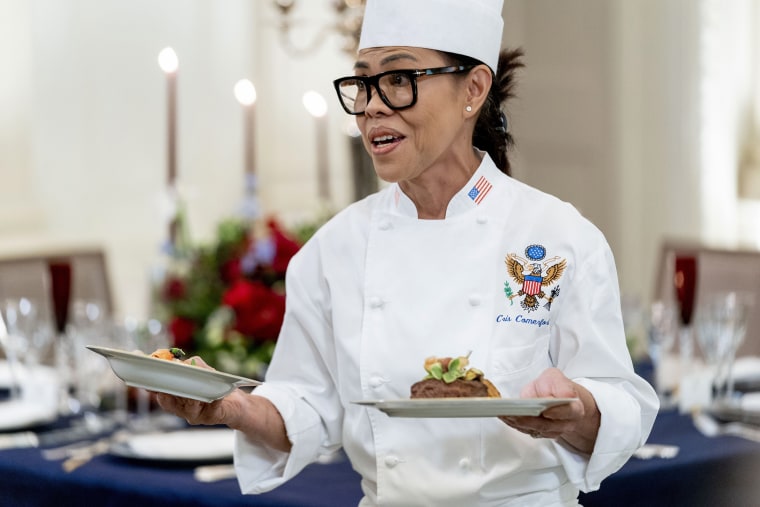 White House executive chef Cris Comerford, holds dishes as she speaks during a media preview for the State Dinner with President Joe Biden and French President Emmanuel Macron in the State Dining Room of the White House in Washington, Wednesday, Nov. 30, 2022. The dinner will include a butter poached maine lobster, a calotte of Beef with shallot Marmalade, American artisanal cheeses, and an orange chiffon cake for desert. (AP Photo/Andrew Harnik)