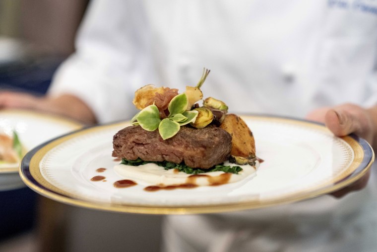 White House executive chef Cris Comerford holds a dish during a media preview for the State Dinner with President Joe Biden and French President Emmanuel Macron in the State Dining Room of the White House,  in Washington, Wednesday, Nov. 30, 2022. The dinner will include a butter poached Maine lobster, beef with shallot marmalade, American artisanal cheeses, and an orange chiffon cake for desert. (AP Photo/Andrew Harnik)