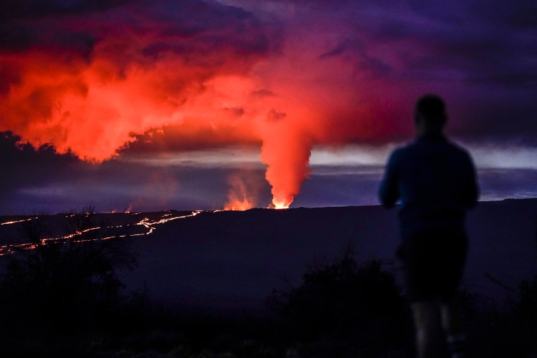 Image: A man looks on as lava erupts from Hawaii's Mauna Loa volcano on Nov. 30, 2022, near Hilo, Hawaii.