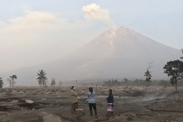 Volcanic ash coats the ground as Mount Semeru looms in the background in Kajar Kuning village in Lumajang, Indonesia, on Monday.