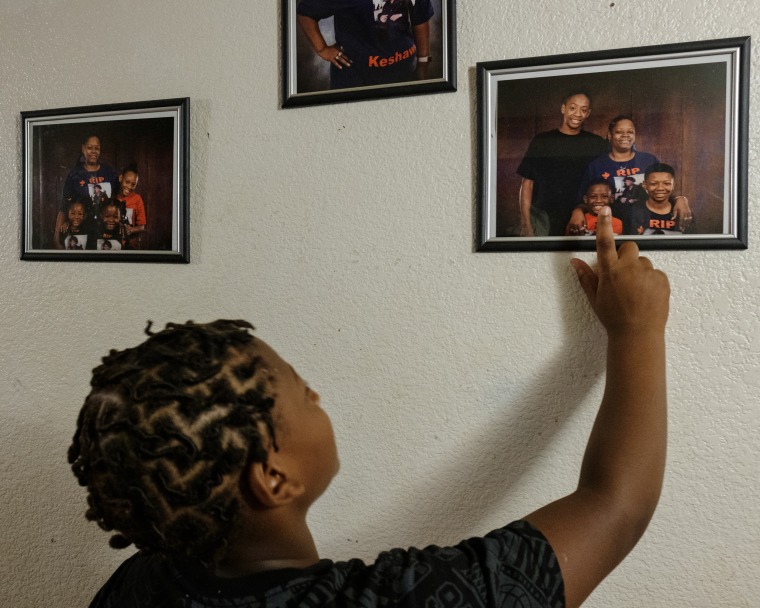Young boy looking at family photos on the wall.