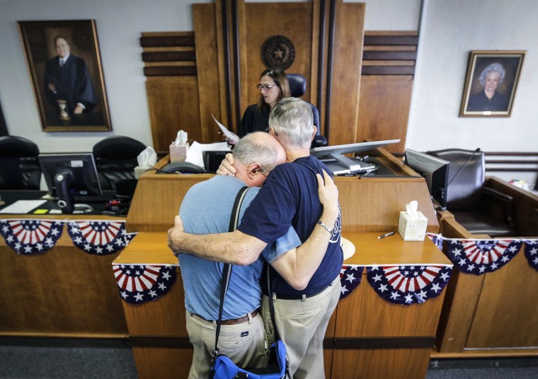 Gerald Gafford, right, comforts his partner of 28 years, Jeff Sralla, left, as they stand before Judge Amy Clark Meachum to obtain a time waiver at the Travis County Courthouse in Austin, Texas on June 26, 2015 after the U.S. Supreme Court ruled that same-sex couples have the right to marry nationwide.