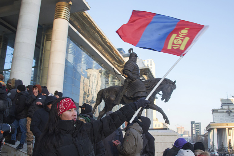 A protester waves a Mongolian national flag as protesters gather on the steps of the State Palace in Ulaanbaatar, Mongolia