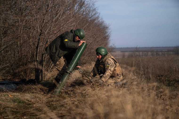 Ukrainian soldiers fire a mortar launcher at a position along the front line in Donetsk region