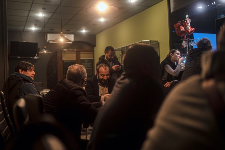 Люди смотрят чемпионат мира по футболу 2022 года в ресторане, питающемся от генератора, после того, как дрон отключил электричество в Одессе, Украина.